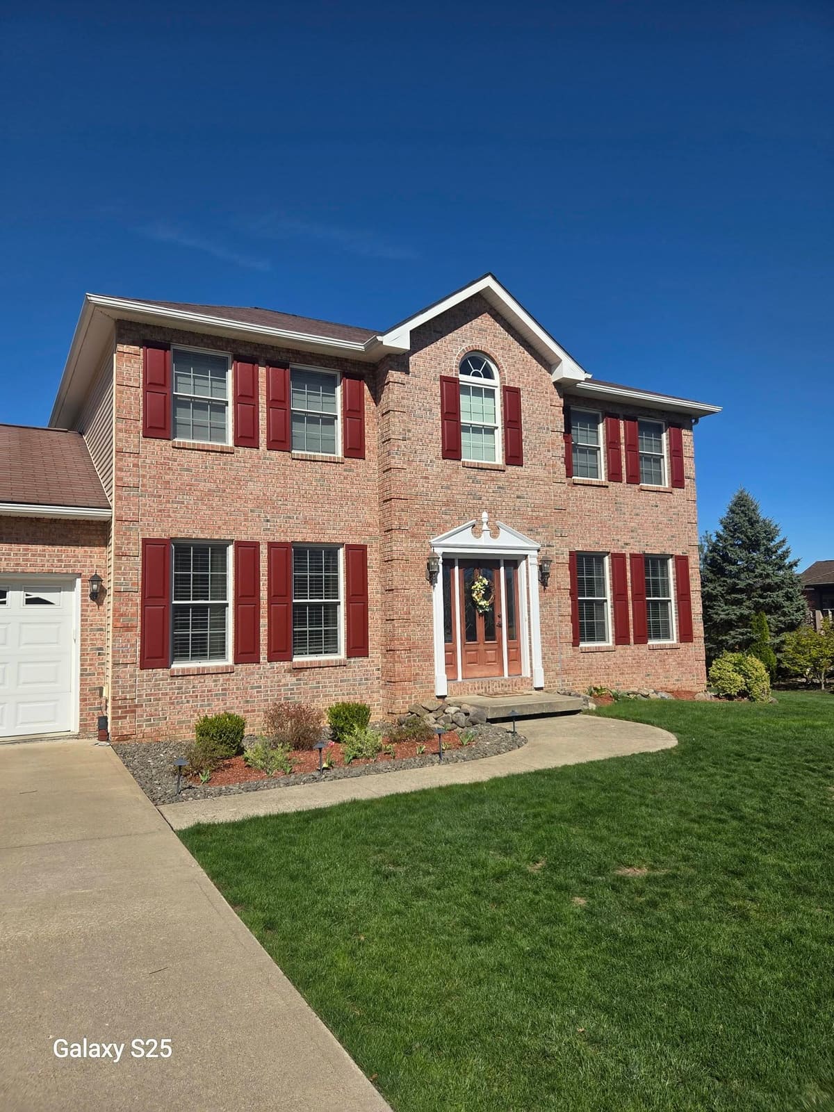 Two story brick colonial home with bright clean siding and trim after a house wash