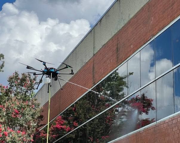 Cleaning drone washing the upper windows of a commercial building