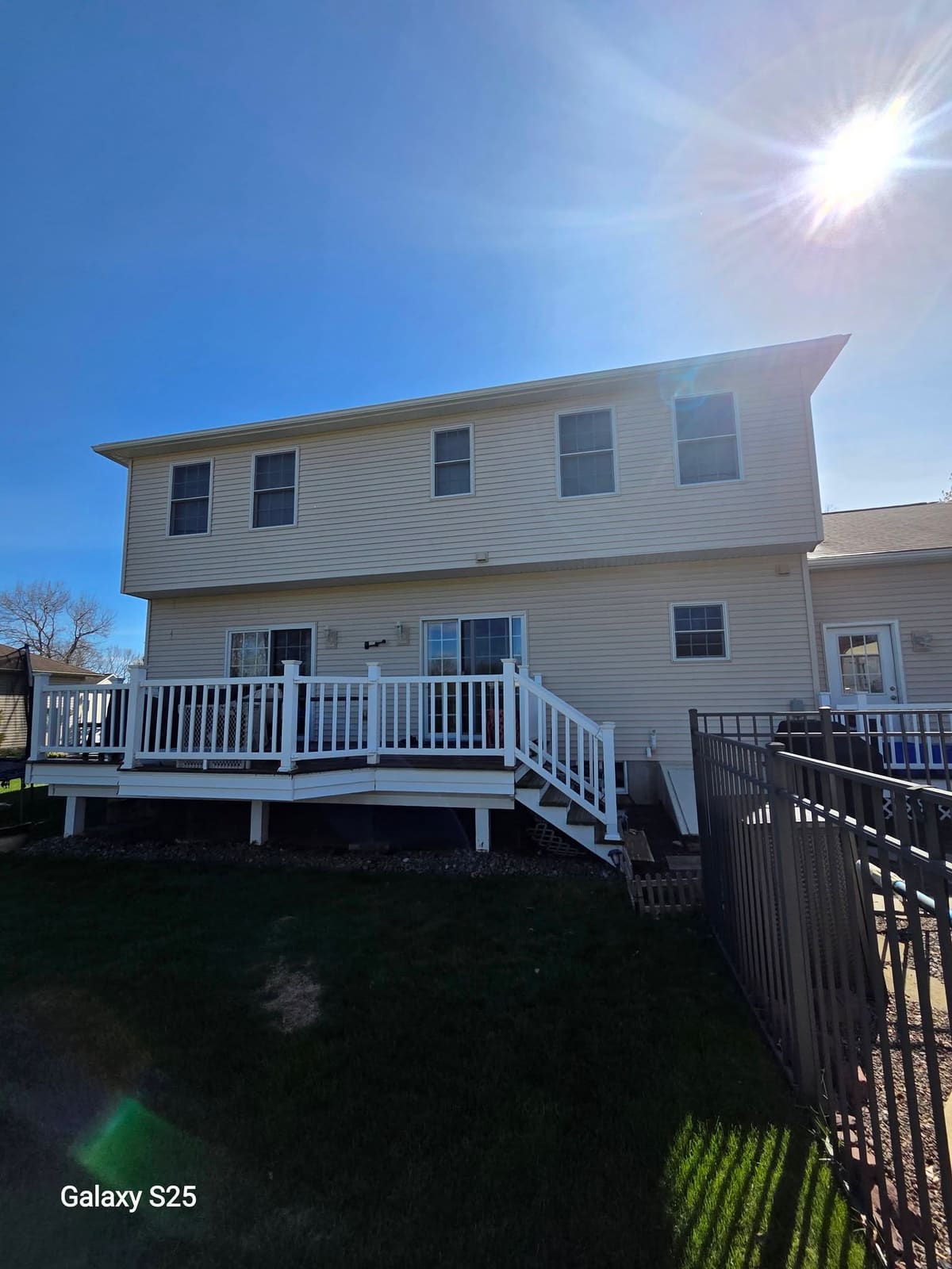 Two story home with clean siding and a white deck rail after soft washing